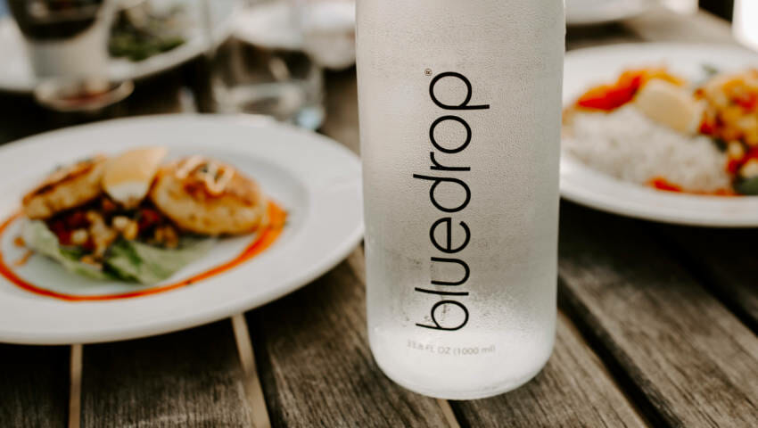 A bottle of bluedrop water on a table at a restaurant.